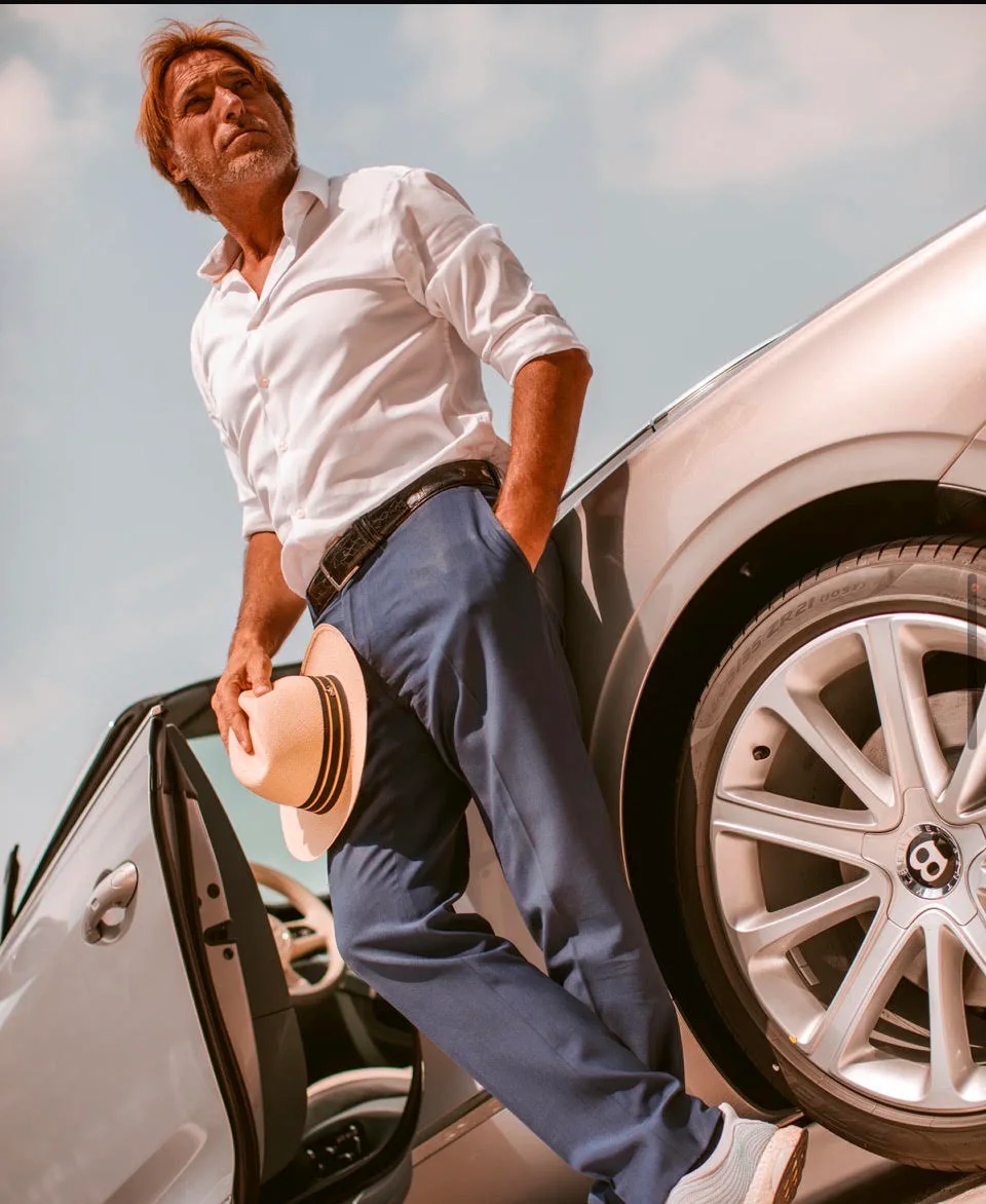 Marco Tibiletti holding a Panama beside a Bentley